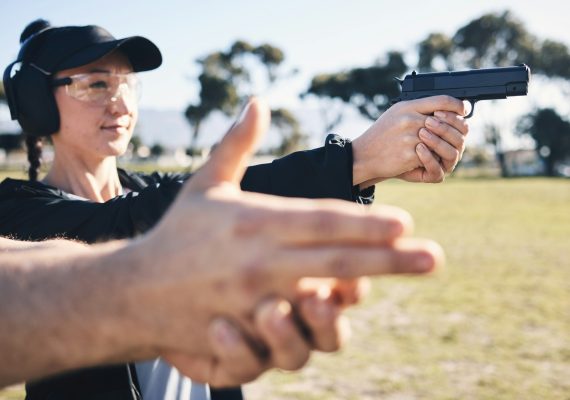 Man, woman and gun training with aim, outdoor target or hand position at police, army or security a